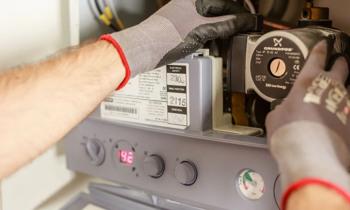 Entretien d’une installation de chauffage, détail des mains gantées et du circulateur